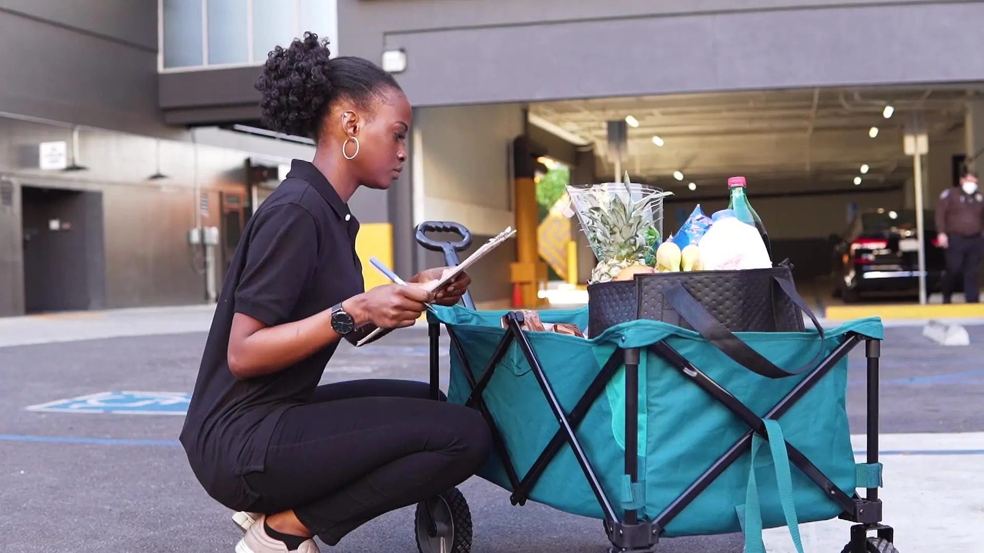 Grocery shopper kneeling by her cart, checking items off the order